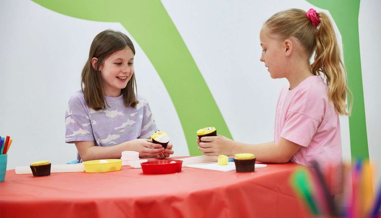 Two girls comparing their cupcake creations.