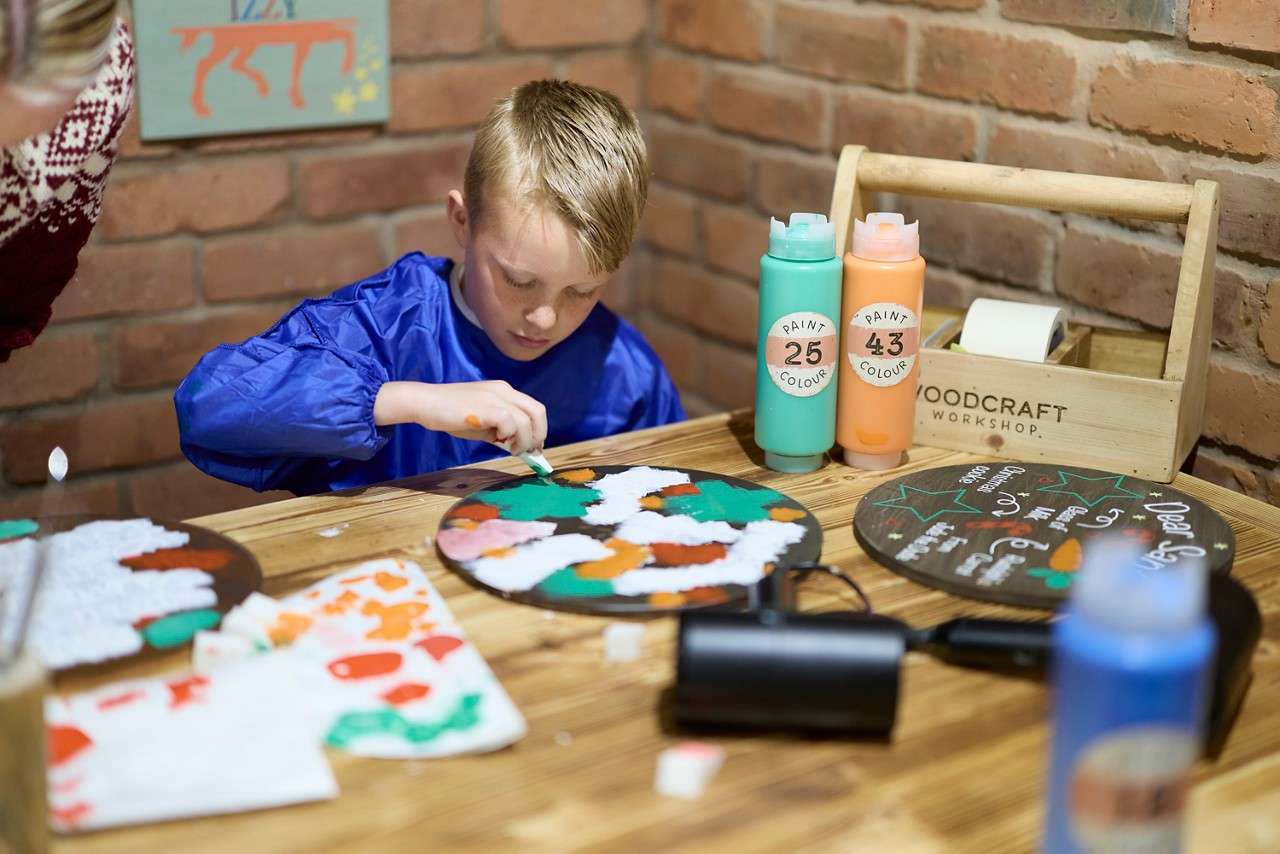 Young boy painting a wooden plaque.
