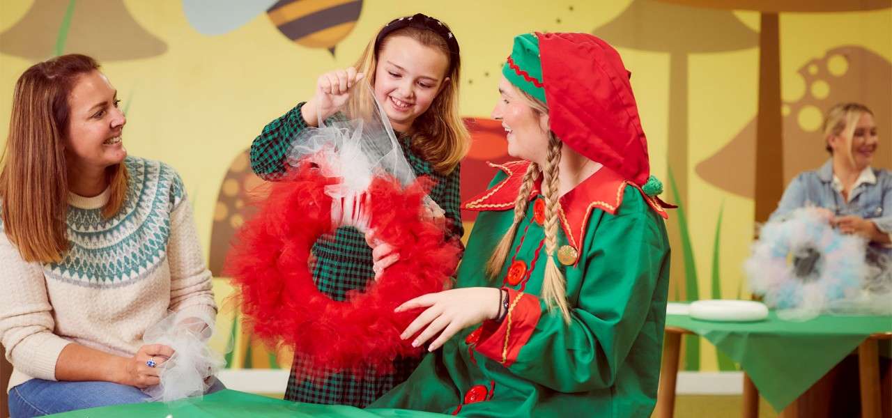 Child making a wreath with the help of an elf