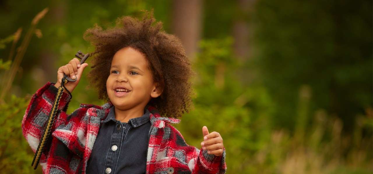 Young girl running through the woods holding a key.