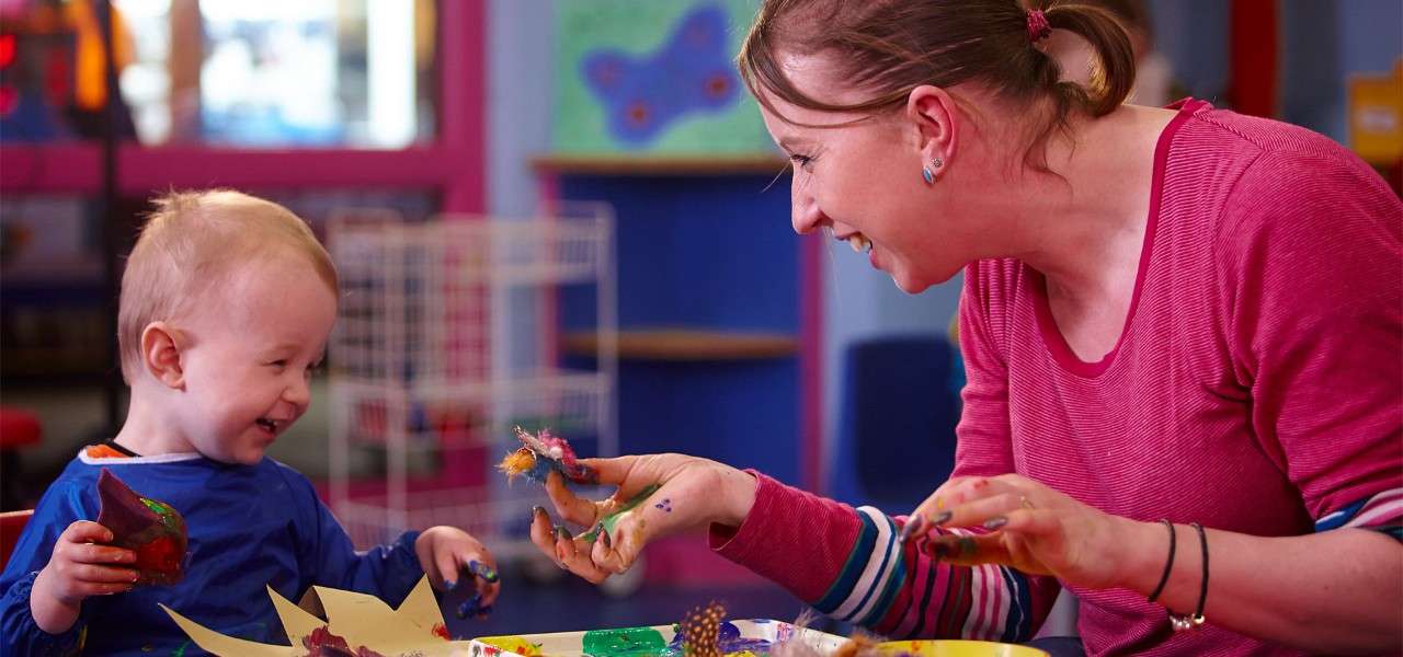 Woman and a toddler enjoying some messy play in the Activity Den.