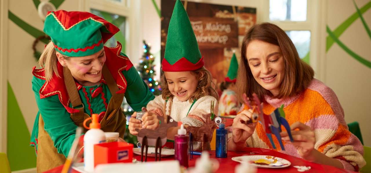 Young girl with an elf taking part in a toy making workshop 