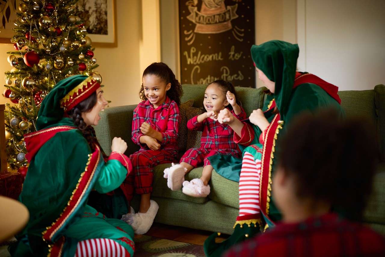 children in matching christmas pjs surrounded by elves in velvet green capes
