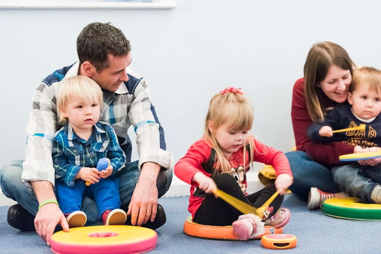 A group of toddlers making music with drums, rattles and other instruments.