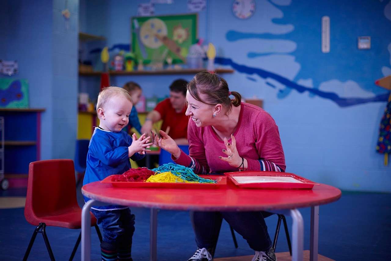 Infant sitting whilst they enjoy some messy crafts with an adult.
