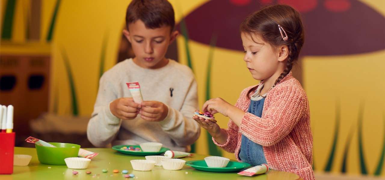 Young boy and girl decorating Winter Cookies in the Activity Den.