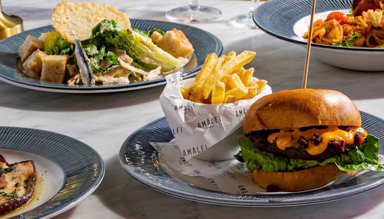 Multiple plates of food including a burger served with fries