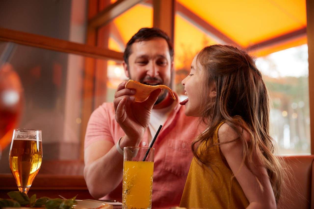 Man with a young child eating pizza.