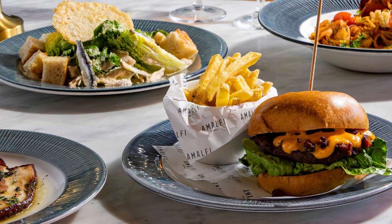 Multiple plates of food including a burger served with fries
