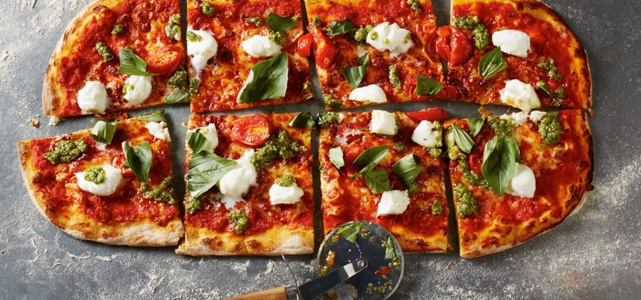 Pizzza topped with basil and pesto.