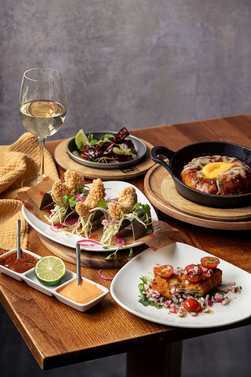 Scoops of sorbet sit in a glass dish, garnished with a mint sprig; one pale yellow and two red; placed on a napkin-lined plate on a wooden table.