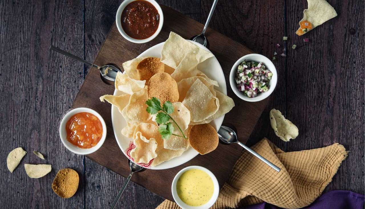 Plate with crispy poppadoms and flavourful dips.