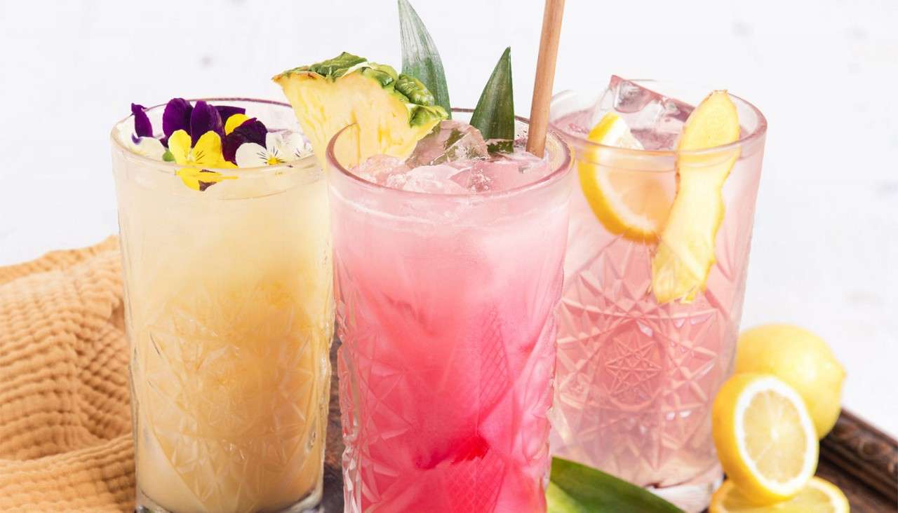 Fresh drinks topped with edible flowers and fresh fruit.