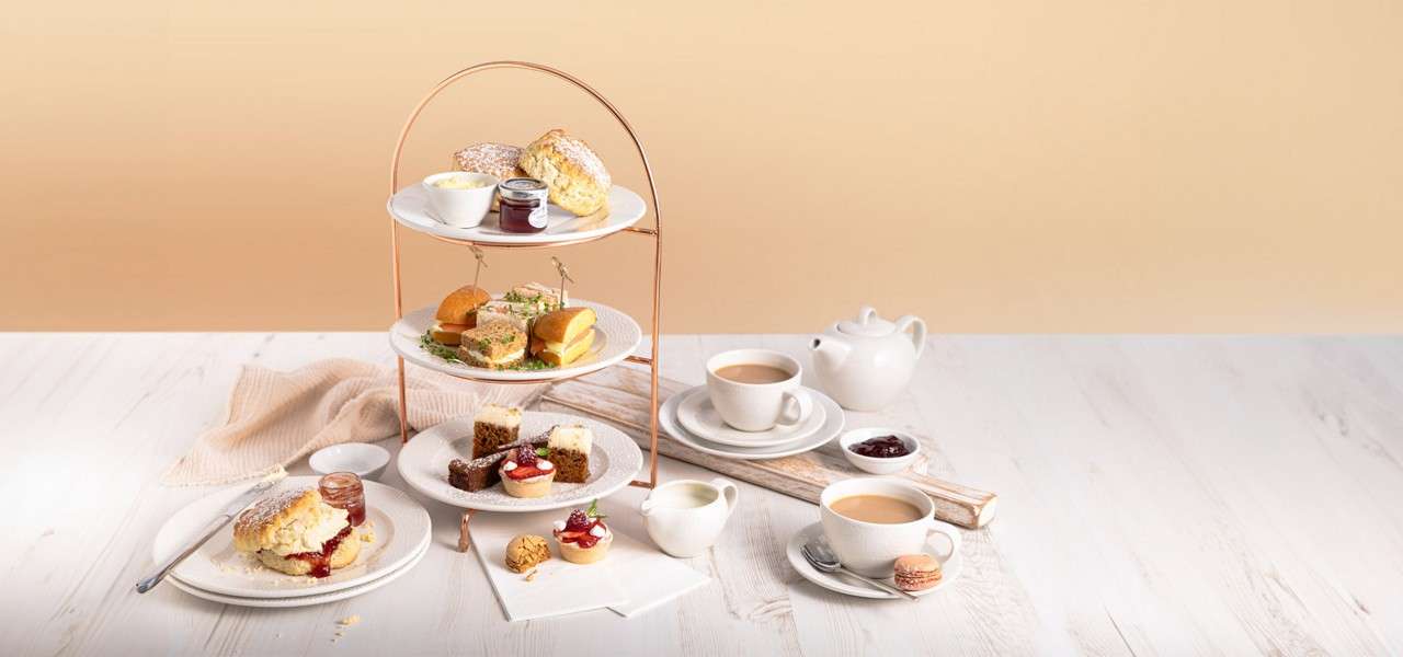 Afternoon tea presented on a stand featuring sandwiches, cakes and scones