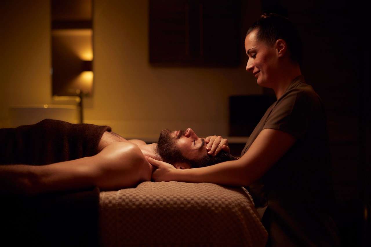 Spa therapist giving a man a relaxing massage treatment whilst lying on a spa bed