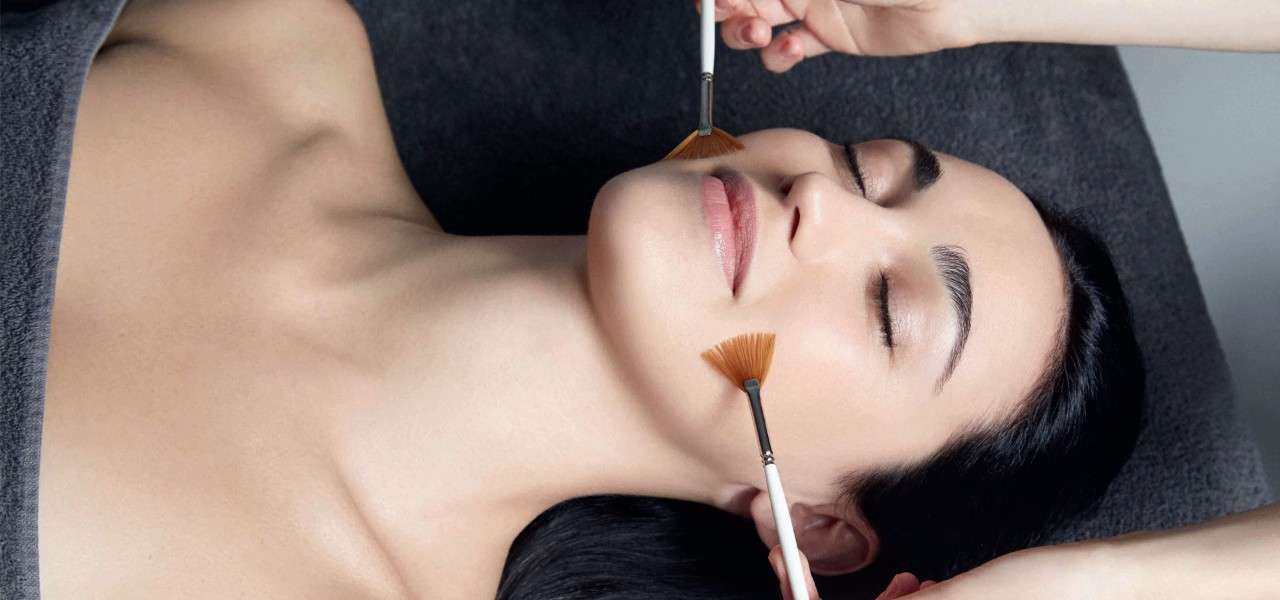 women laid with eyes closed with brushes on her face