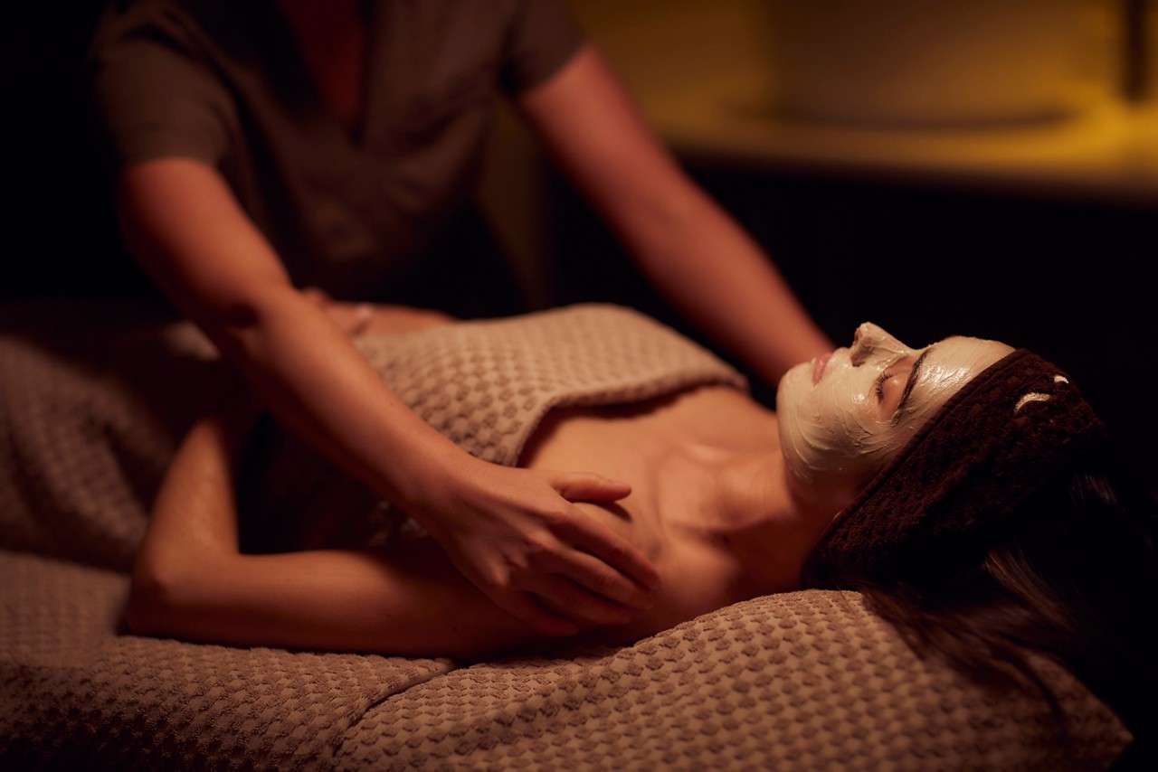 Spa therapist giving a woman a face mask treatment.