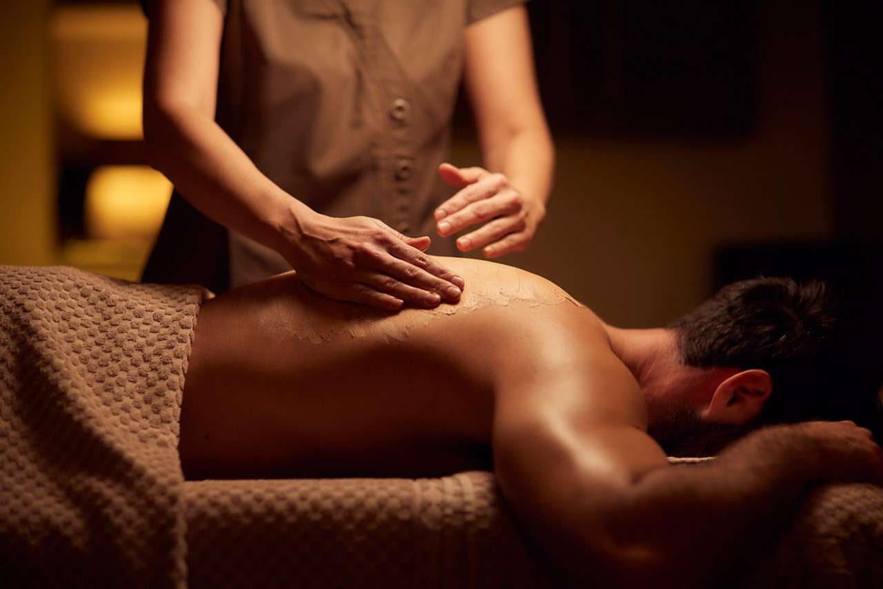 Spa therapist giving a man a relaxing back massage treatment.