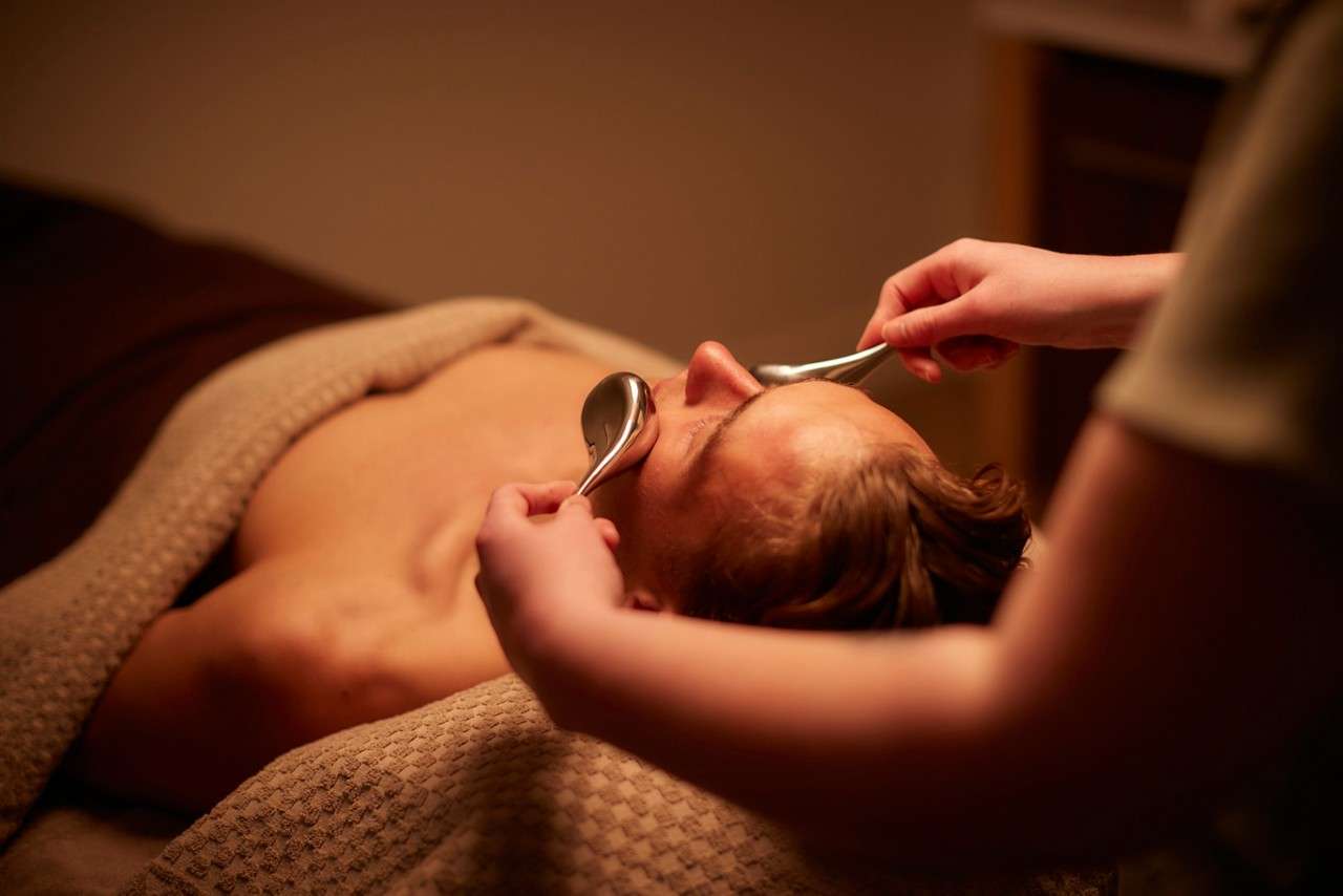 Spa therapist giving a man a relaxing massage treatment whilst lying on a spa bed