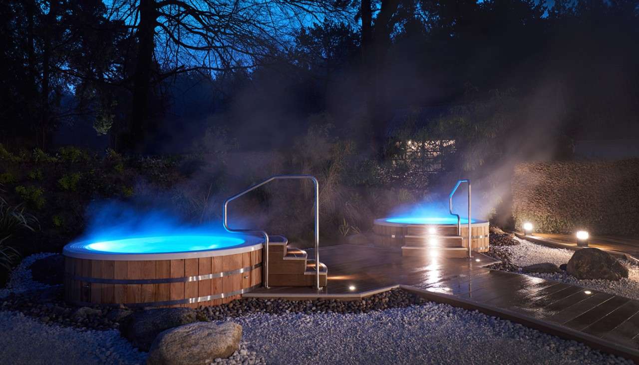 Two steaming hot tubs with stairs leading up to both.