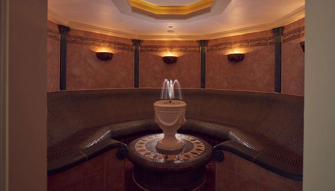 Inside a decorative tiled room surrounding a small fountain.