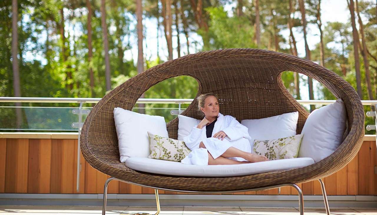 Woman resting in an oval chair on an outdoor terrace.