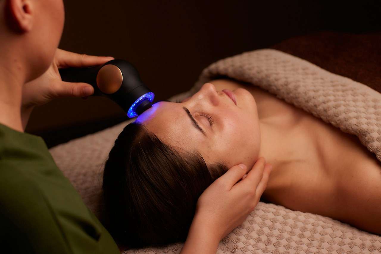 Woman having a facial with a microcurrent handheld device.
