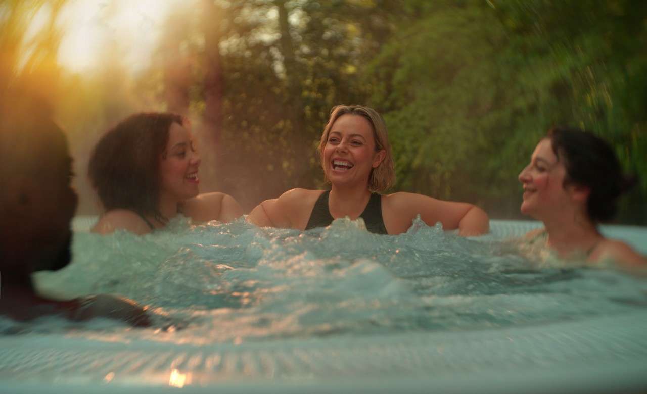 people in an outdoor hottub smiling surrounded by forest