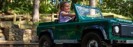 A young girl driving a mini rover thorough the forest