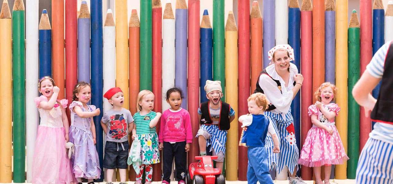 Children dressed up as pirates and princesses in front of a colour pencil fence