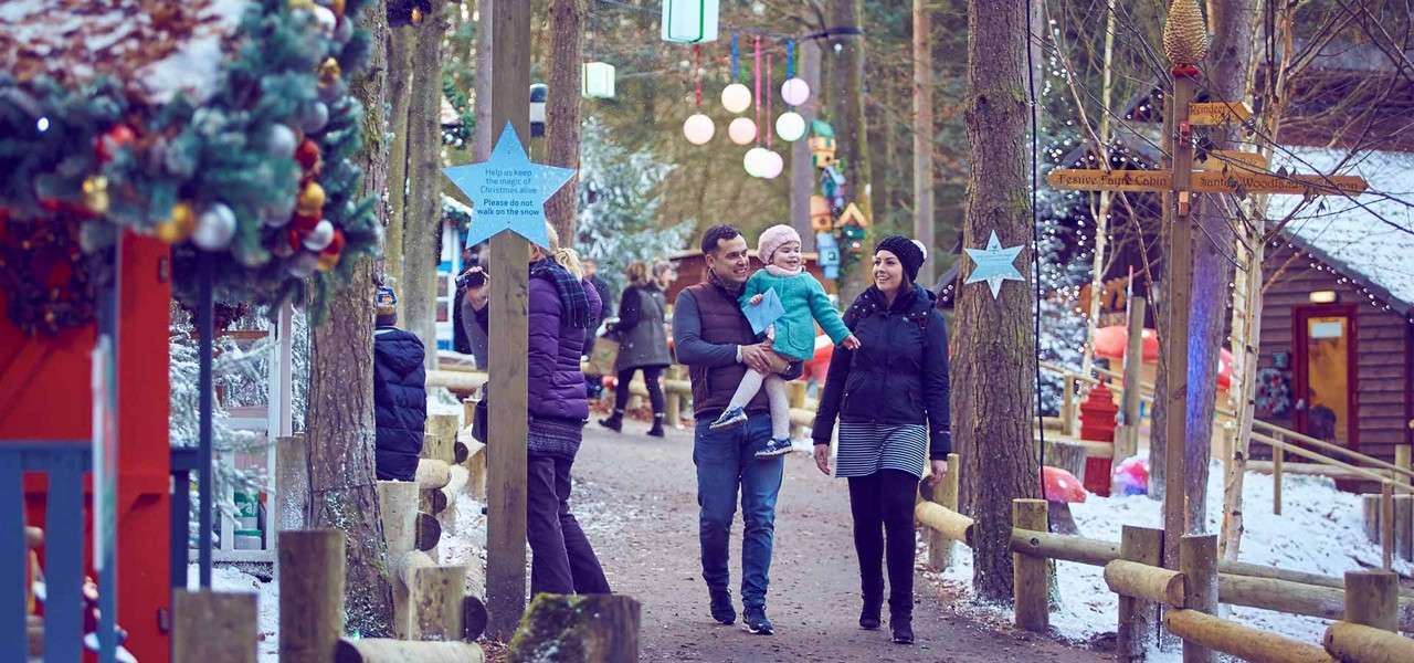 Family walking through Winter Wonderland children wearing jumpers with Rudolf on them