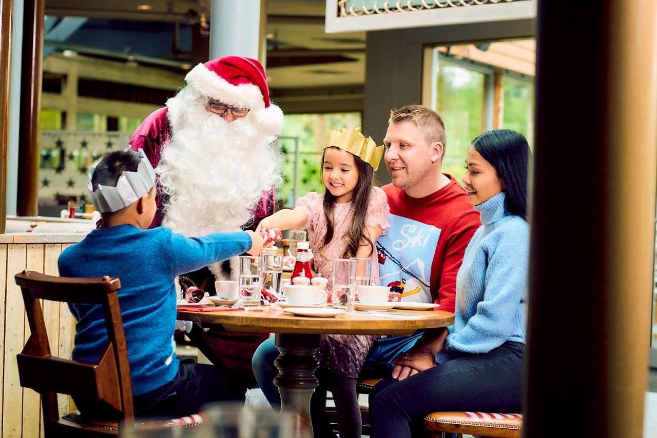 Family sitting around a table whilst Santa comes to visit.