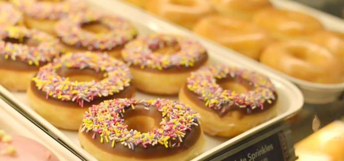Donuts lined up topped with chocolate and sprinkles.