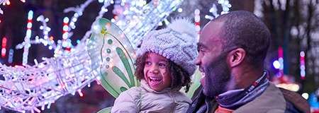 A little girl and her father looking at the Winter Forest Lights.