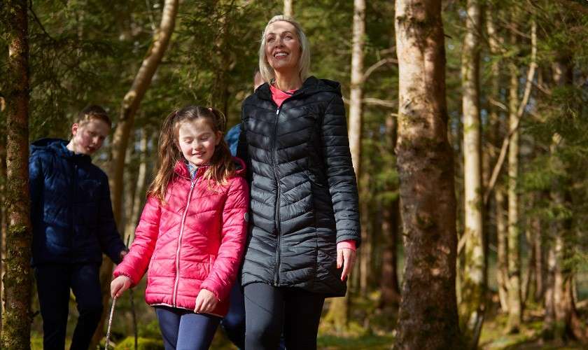 A parent and her two children walking through the woodland