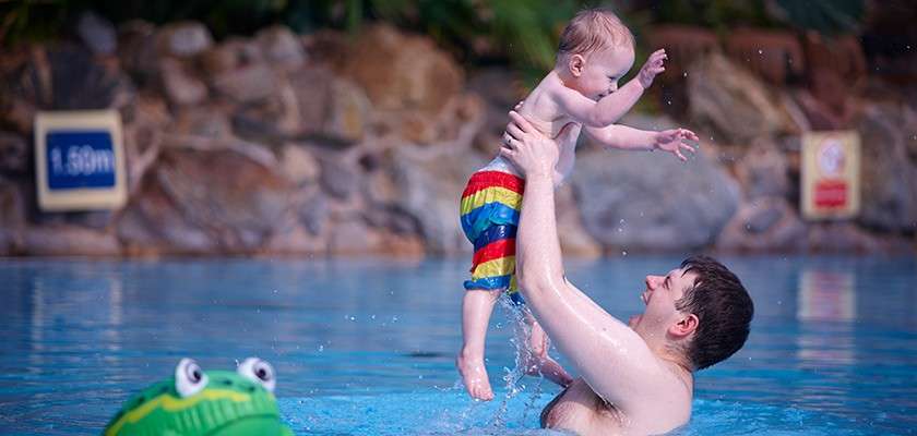 Father splashing with baby in Subtropical Swimming Paradise