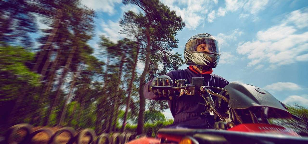 A man wearing a helmet riding a quad bike