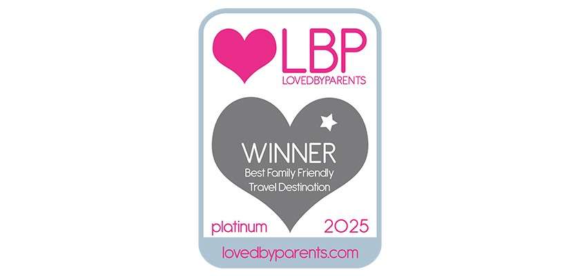Award badge announces recognition; reads: LBP LOVEDBYPARENTS, WINNER Best Family Friendly Travel Destination, platinum 2025, lovedbyparents.com; displayed within a rounded rectangle featuring heart icons.