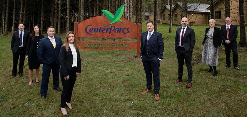 Team members stand around entrance sign to Longford Forest