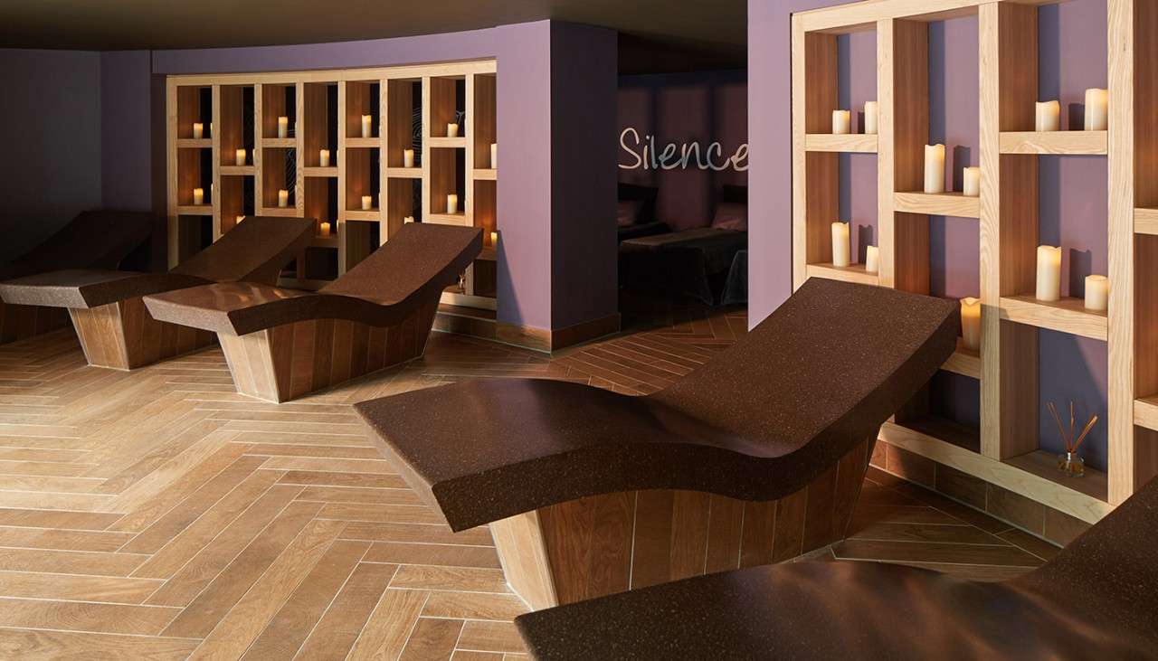 Reclined heated loungers with pillared candles on decorative shelving behind it.