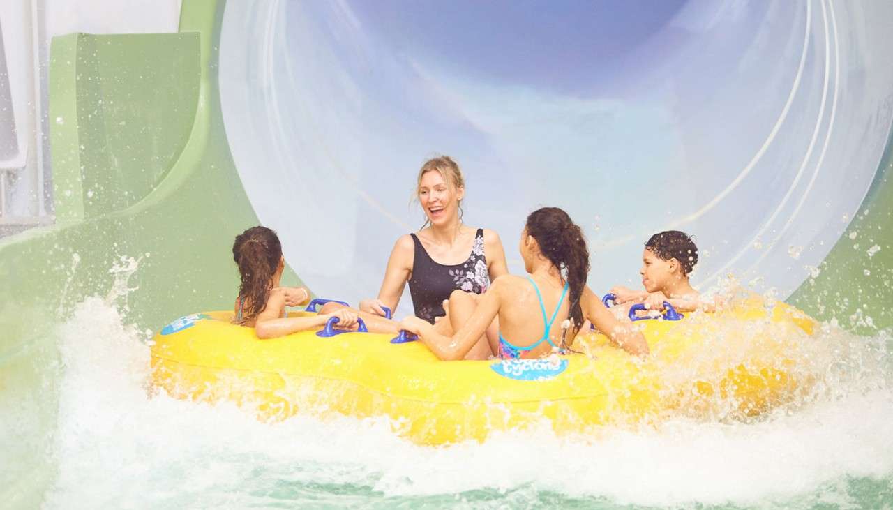 A family on a pool inflatable splashing at the bottom of the Tropical Cyclone.