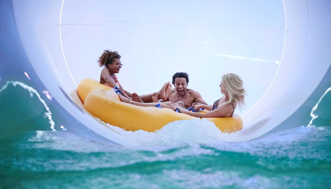 A family on a pool inflatable riding down the Tropical Cyclone.