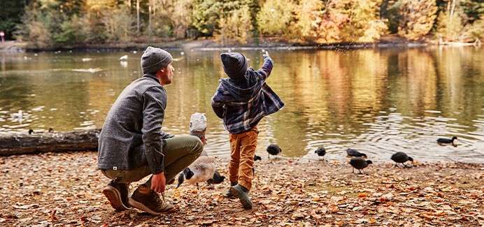 Father and son feeding ducks at the lake