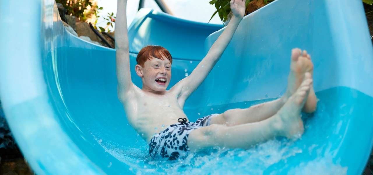 A boy going down a flume slide in the Subtropical Swimming Paradise.