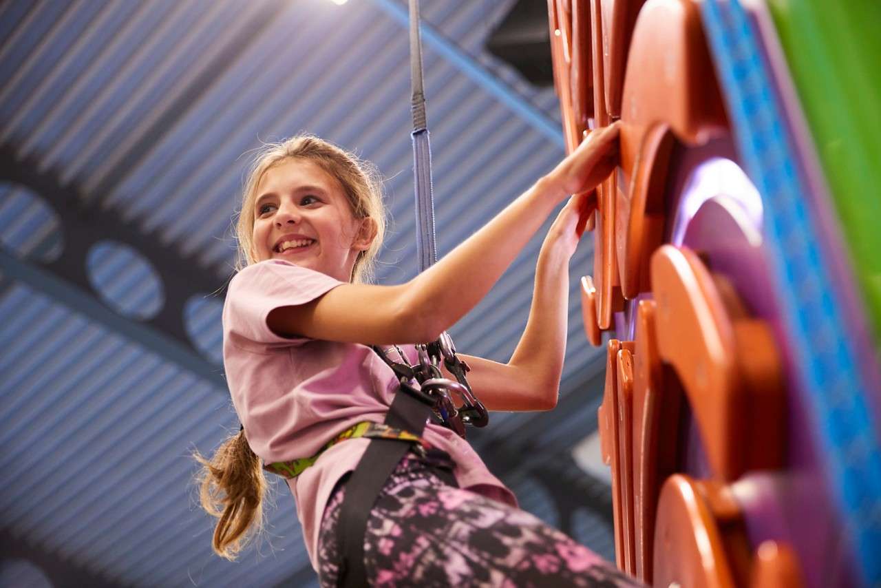 Young girl climbing on an indoor climbing wall.