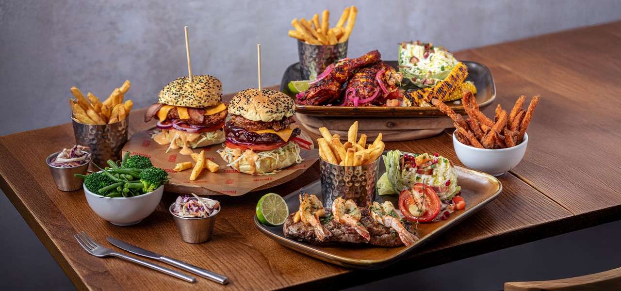 Variety of dishes from the Huck's menu including ribs, wings, fries and charred corn.