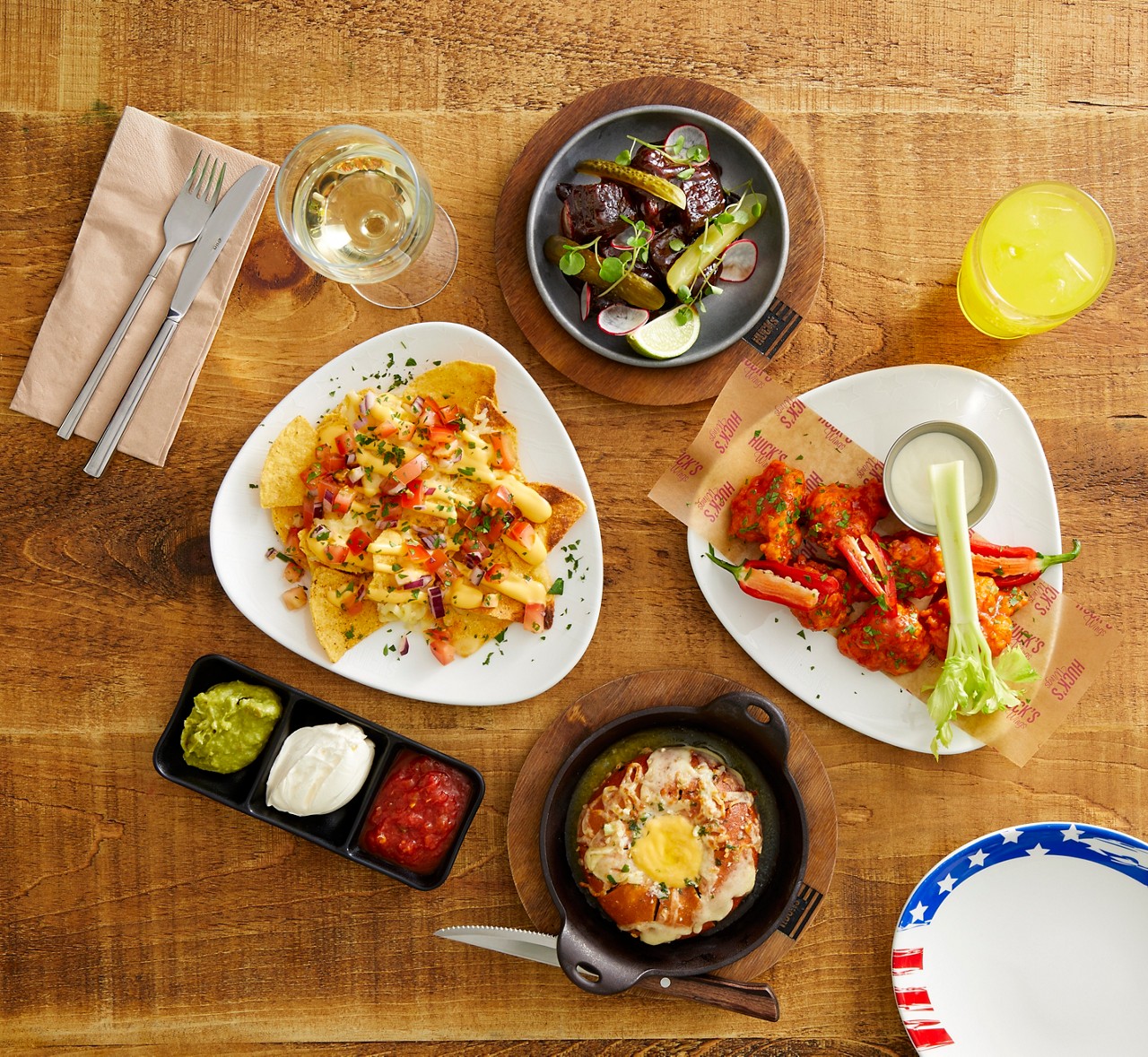 A collection of dishes from the Huck's menu, including nachos, cauliflower wings and cheesy garlic bread.