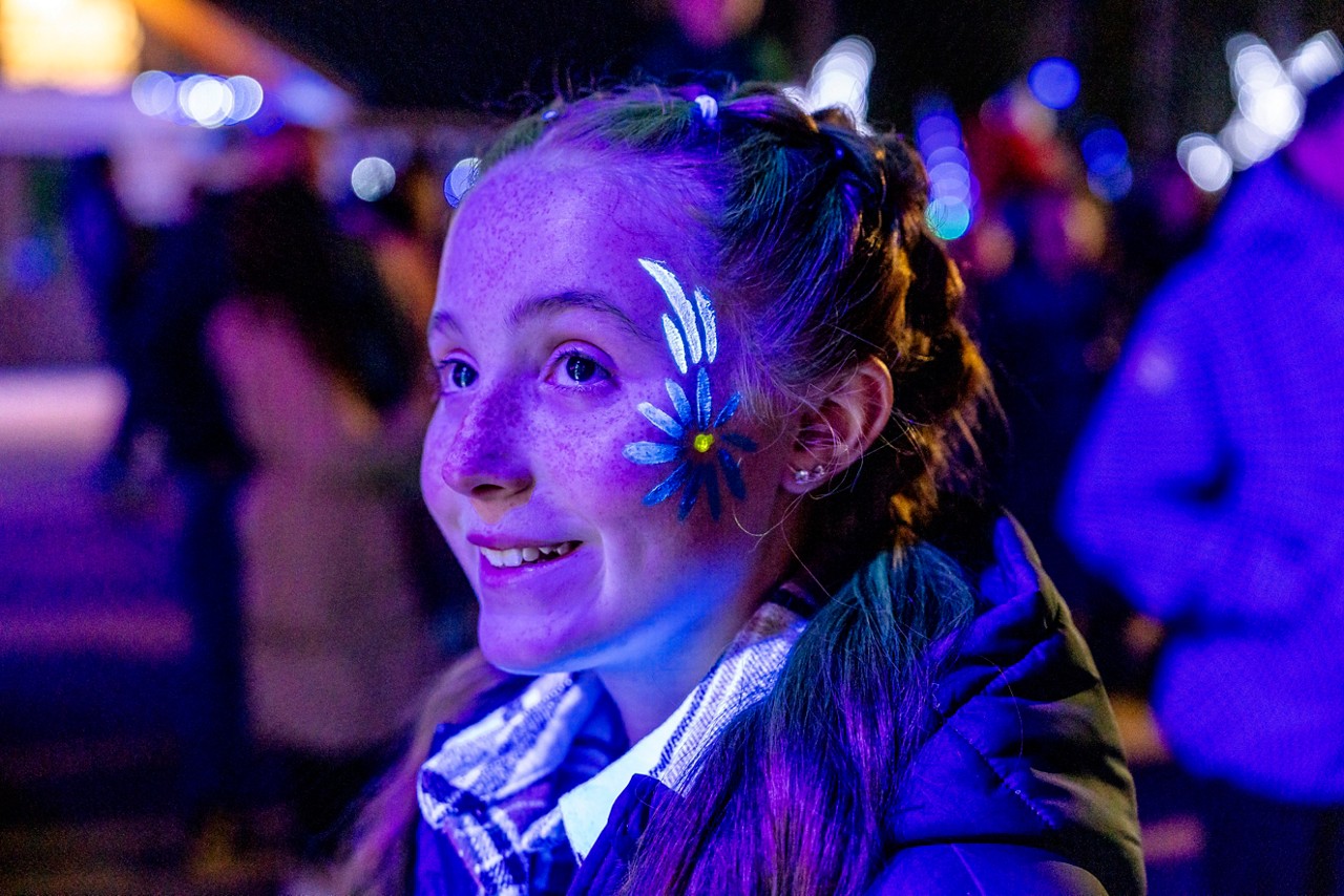 A girl with UV flower face paints on her face