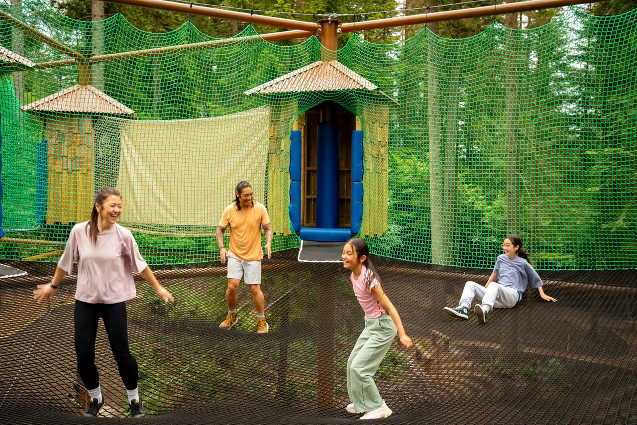 Family jumping in the Adventure Nets course suspended in the trees.
