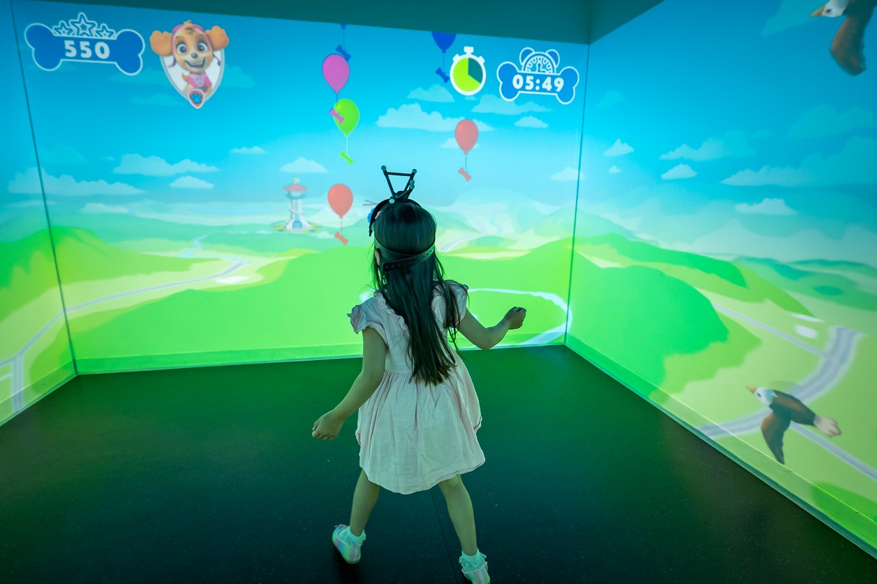 Young girl inside a room with projected images wearing an immersive headset.